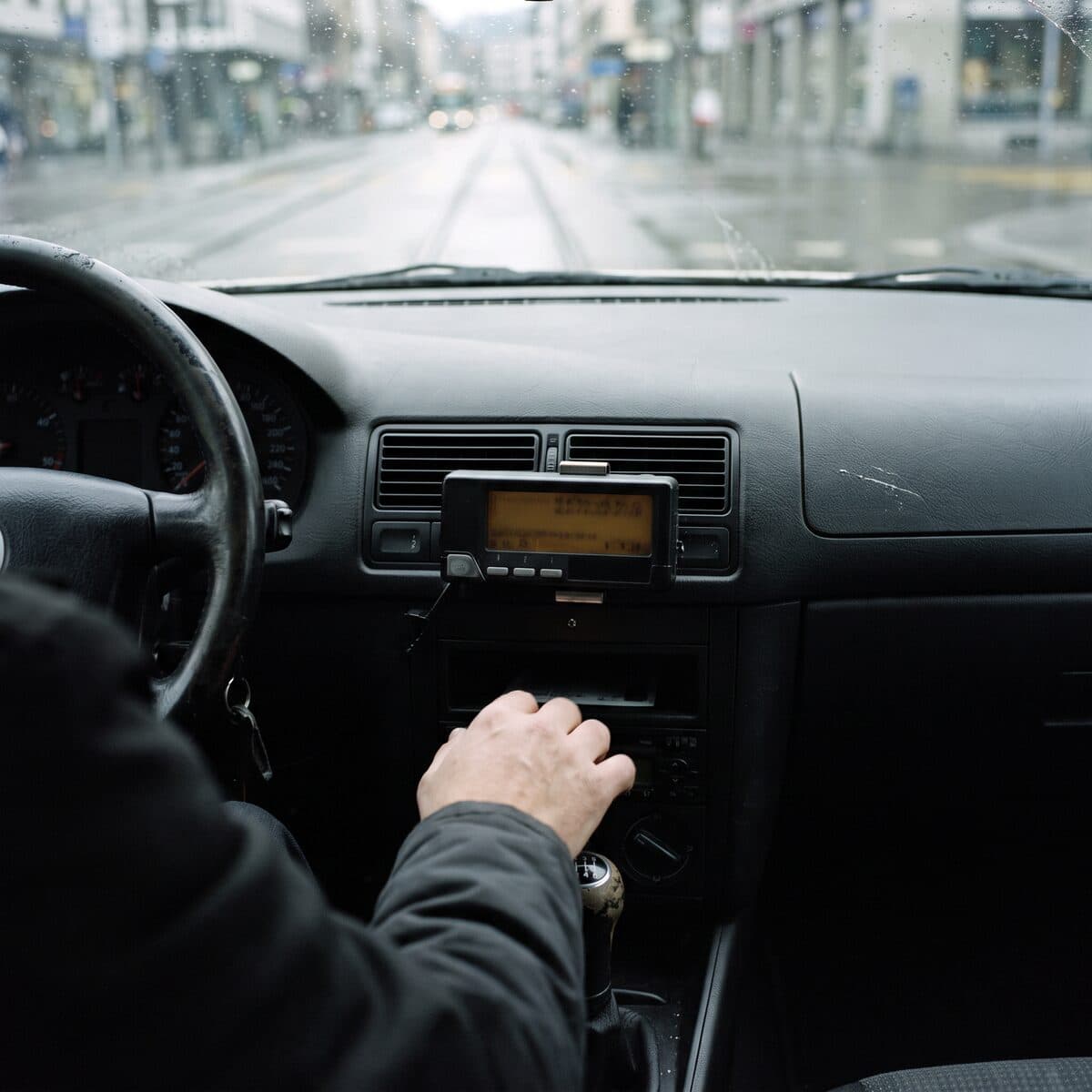 Taximètre et tableau de bord d'un taxi genevois, la main du chauffeur sur le levier de vitesse