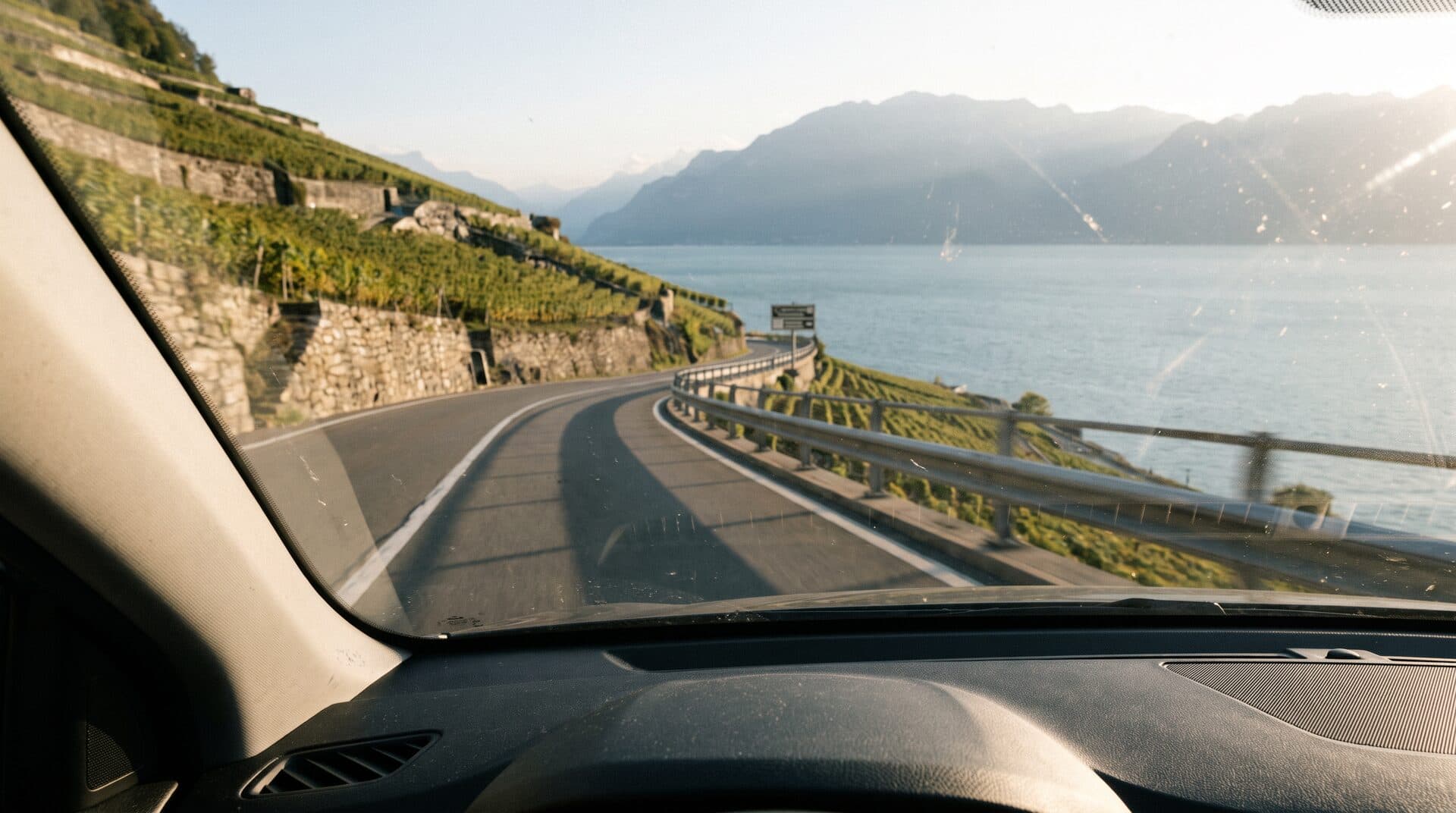 Vue depuis le siège passager d'une voiture sur la route du Léman entre Genève et Lausanne, vignes de Lavaux et lac au soleil couchant